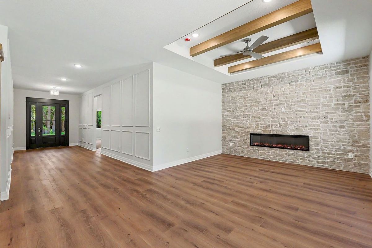 Great room with a stacked-stone fireplace wall and stained timber ceiling beams in the RJ Castle home at 116 S Byron Road – Wichita, KS